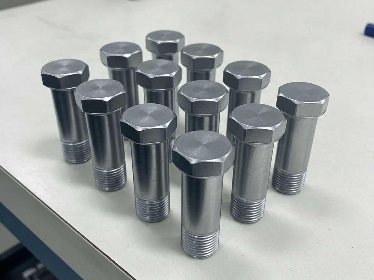 Six identical steel fasteners on a white surface